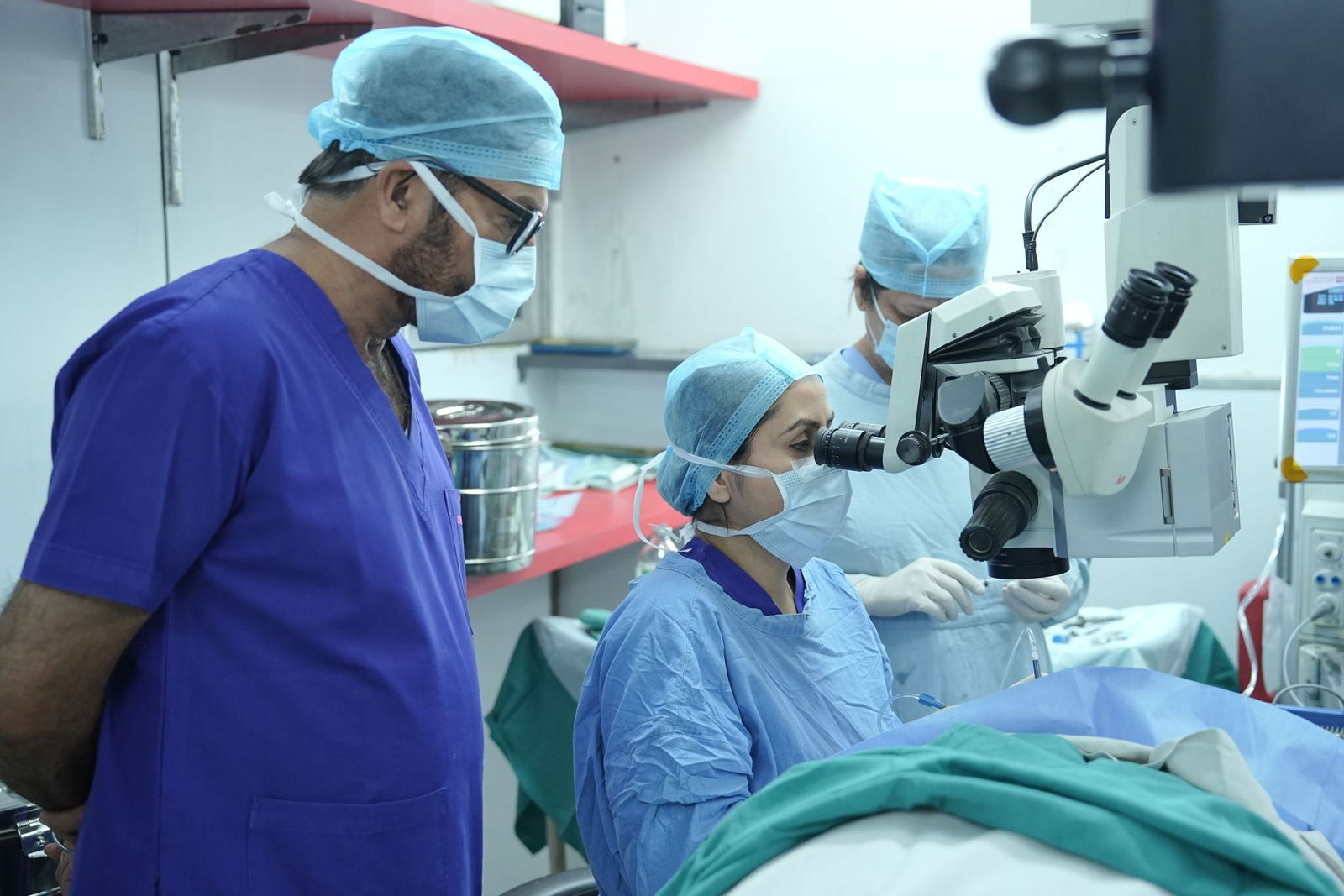 Surgical team working at a microscope during an operation in a hospital theatre