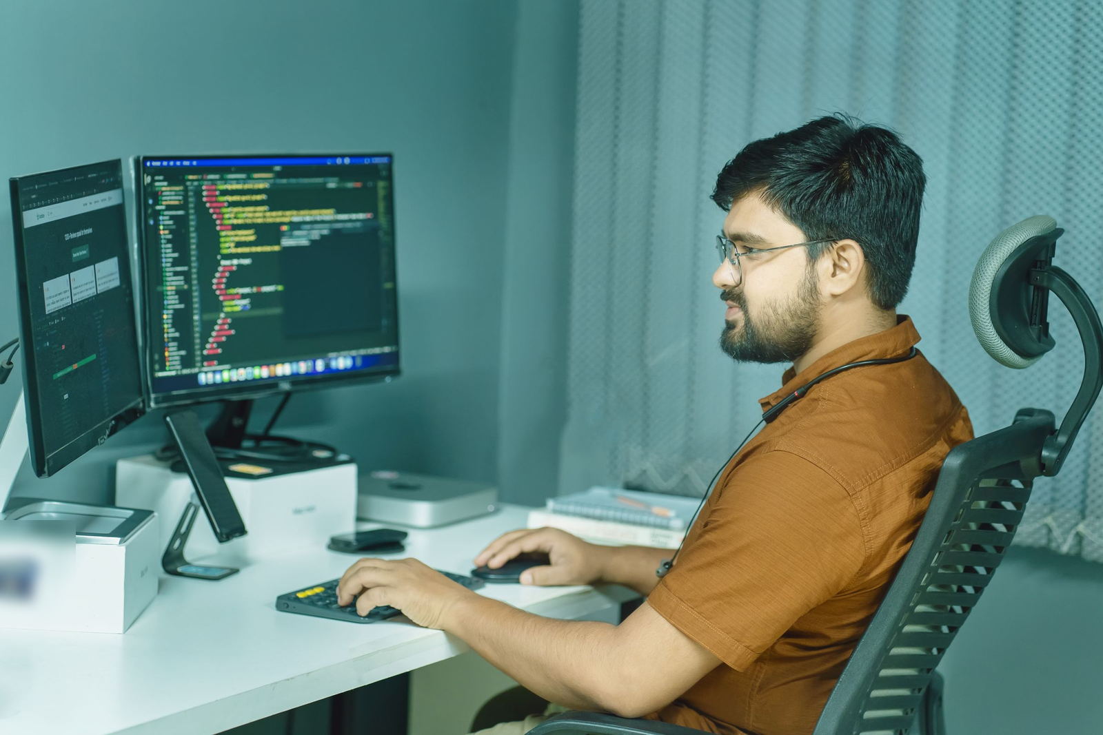 Software developer writing code on a dual-monitor setup in a calm office