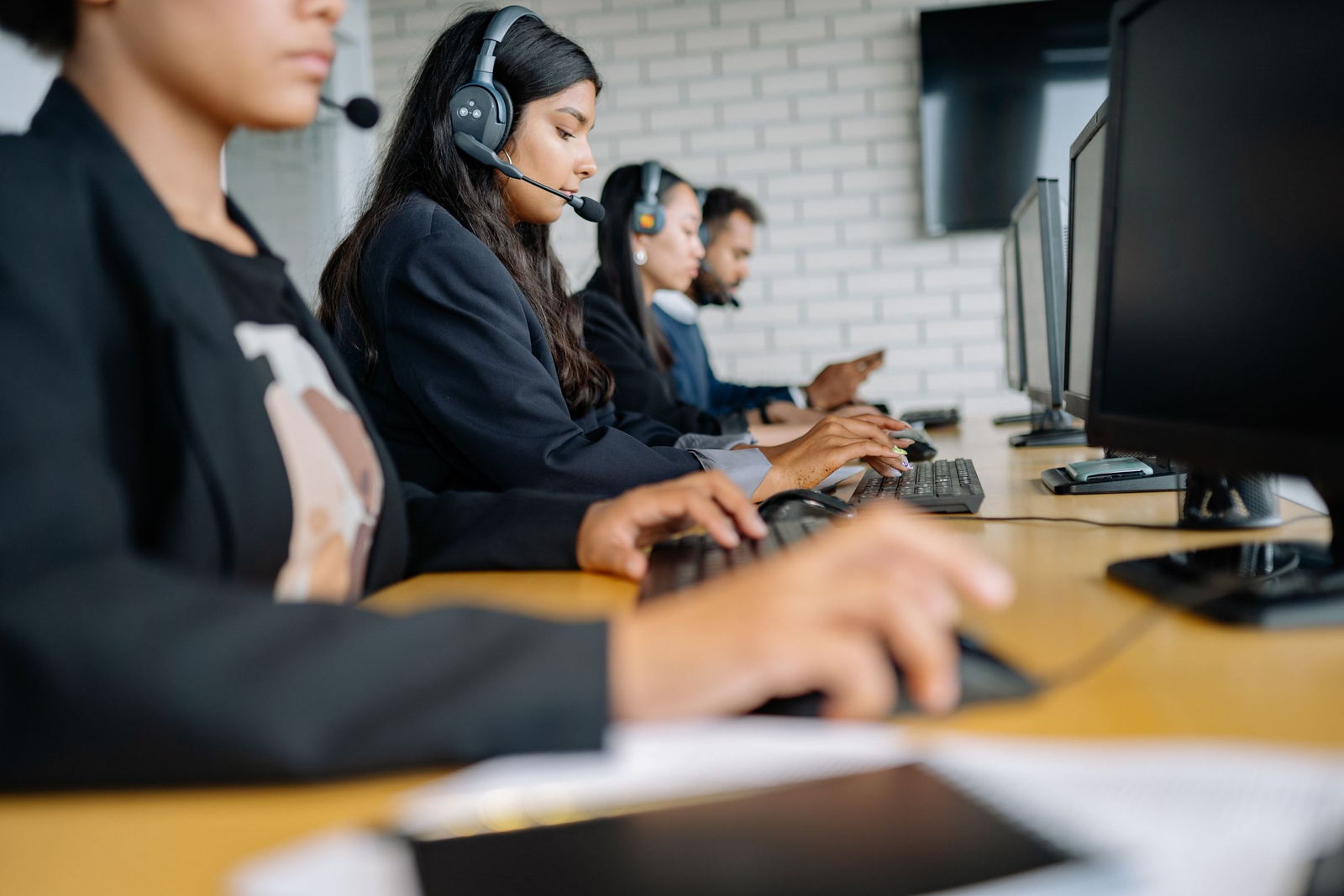 Row of customer support agents in headsets working at their monitors on a BPO floor