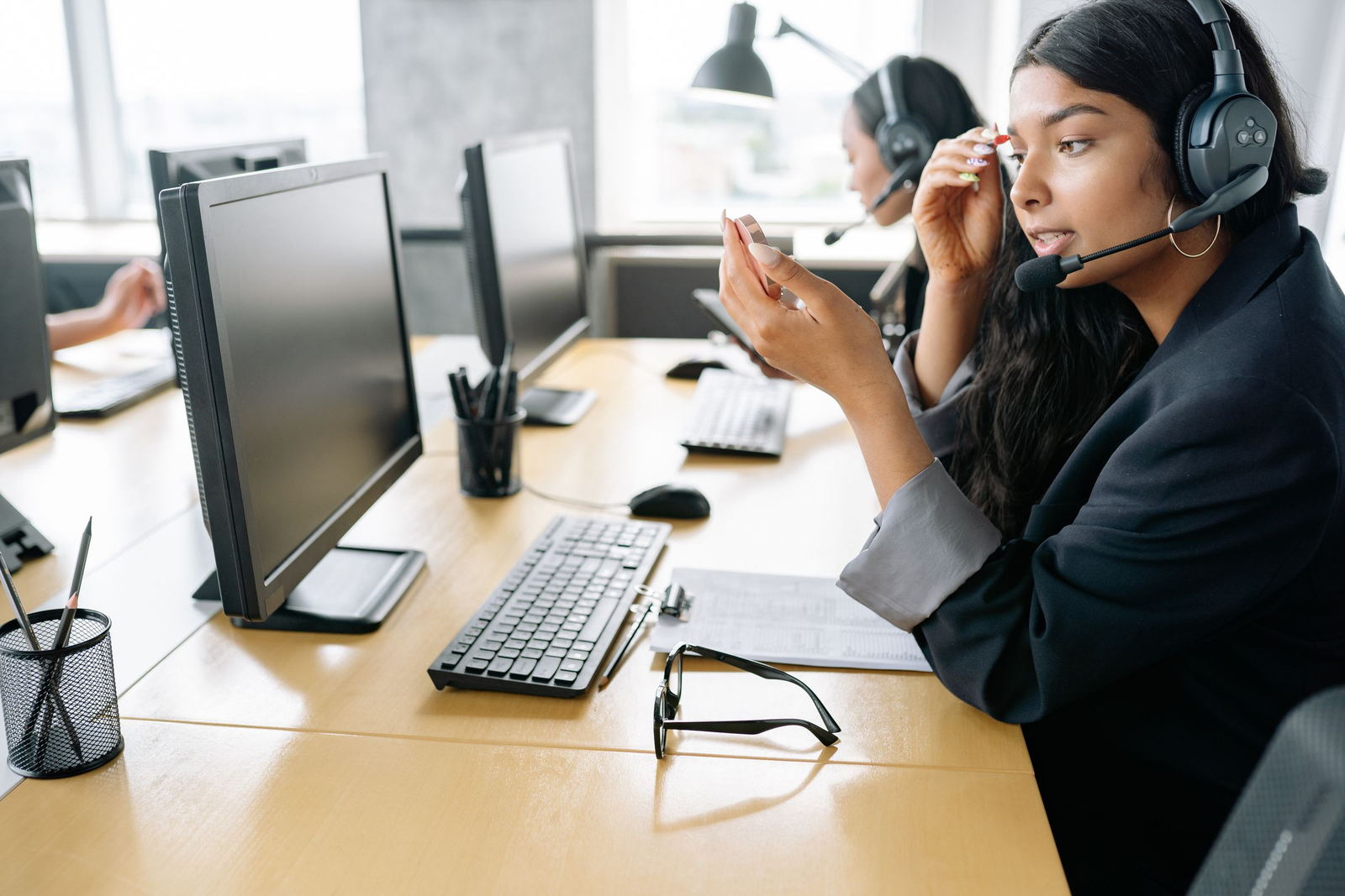 A recruiter wearing a headset works through candidate profiles at a desk in a bright office.