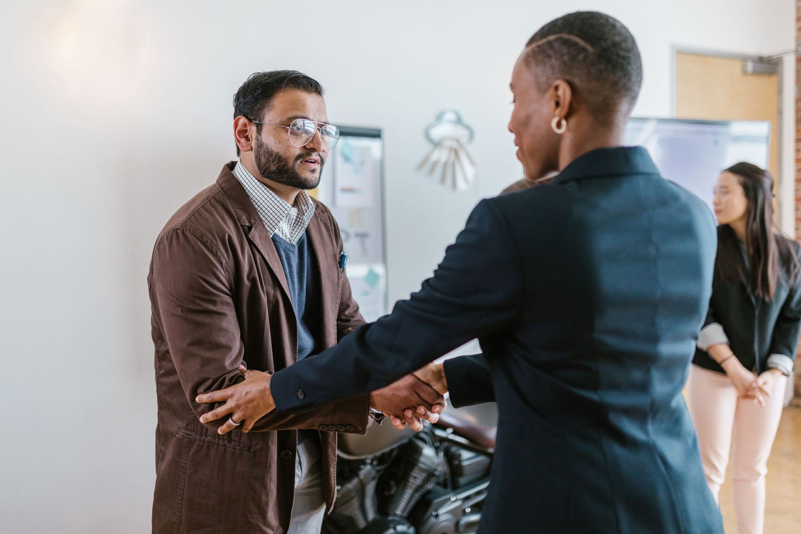 A candidate and a recruiter shaking hands at the end of an interview in a bright office